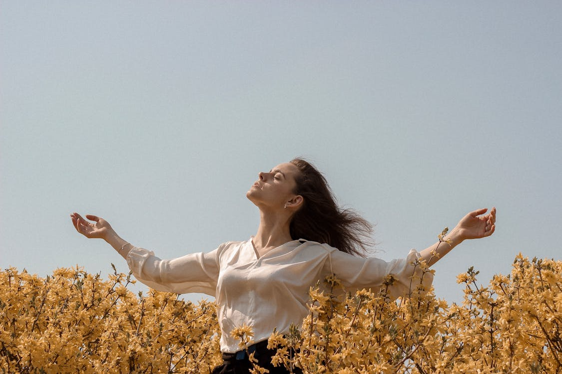 Woman standing in a field of flowers, enjoying fresh air and a sense of freedom