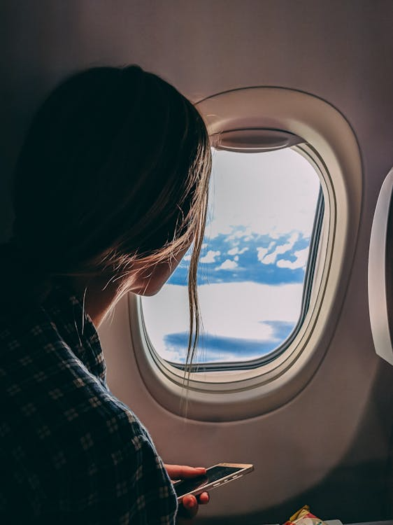 a woman looking outside an airplane window.