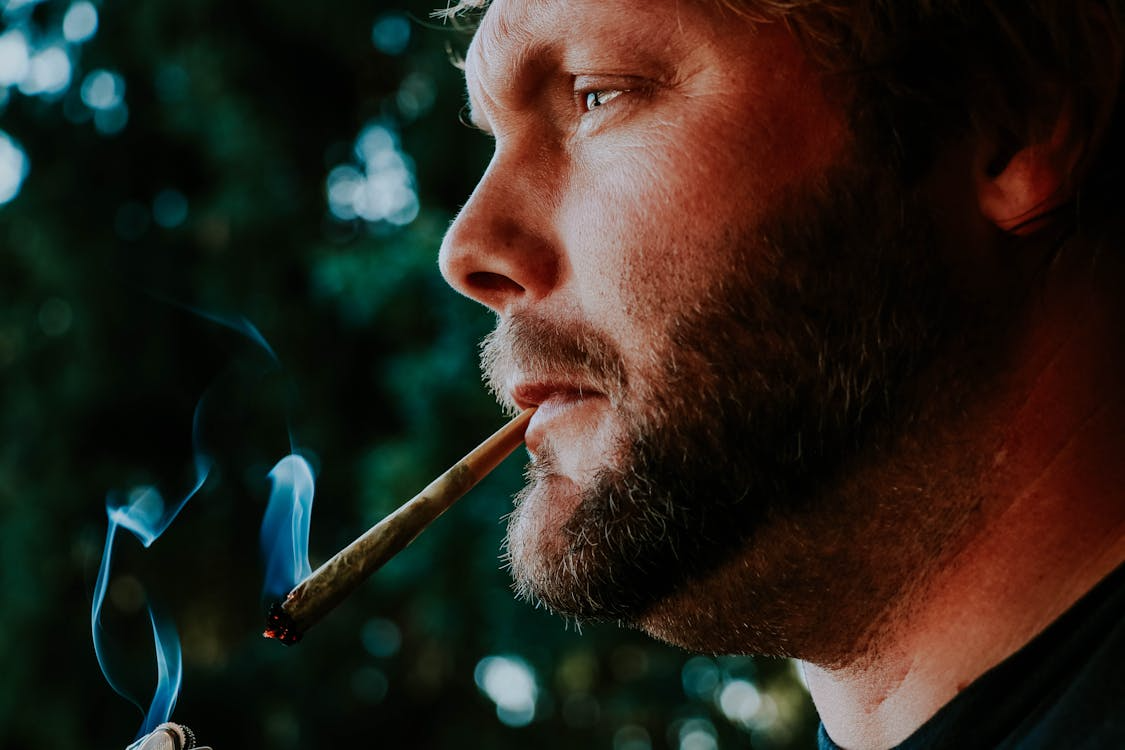 Man smoking a cannabis joint in nature under sunlight