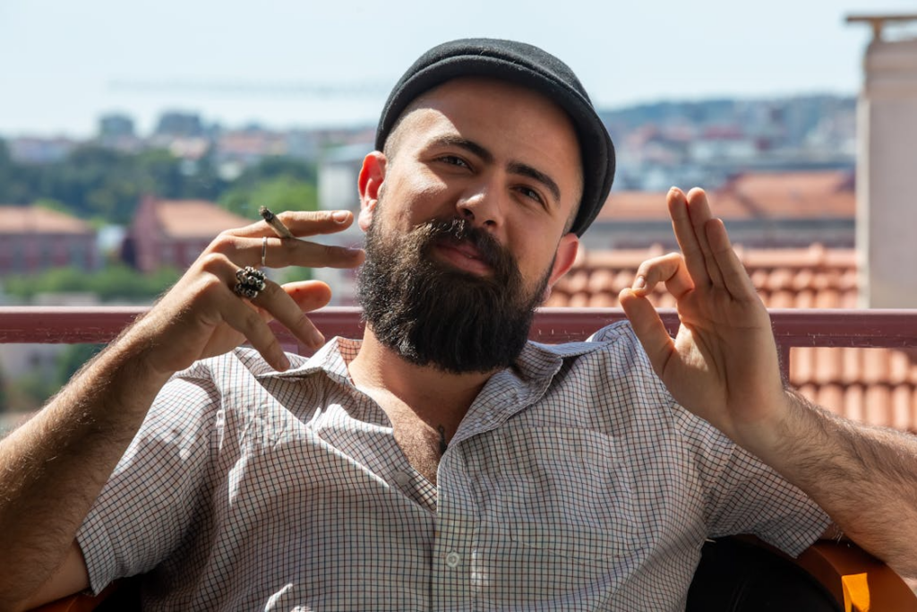 Bearded man enjoying cannabis outdoors with scenic city view