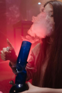 Woman smoking cannabis using a glass bong