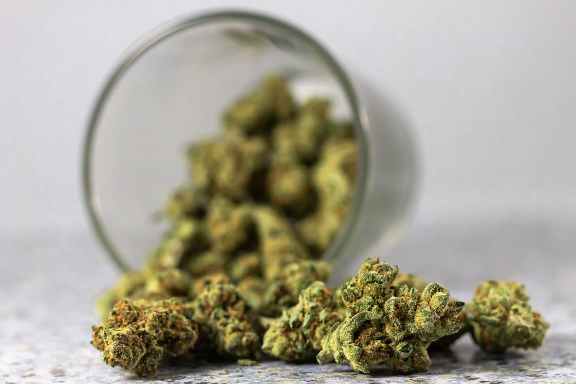 Cannabis buds spilling from a glass jar, highlighting aroma and terpene mood guide concepts for choosing strains based on experience.